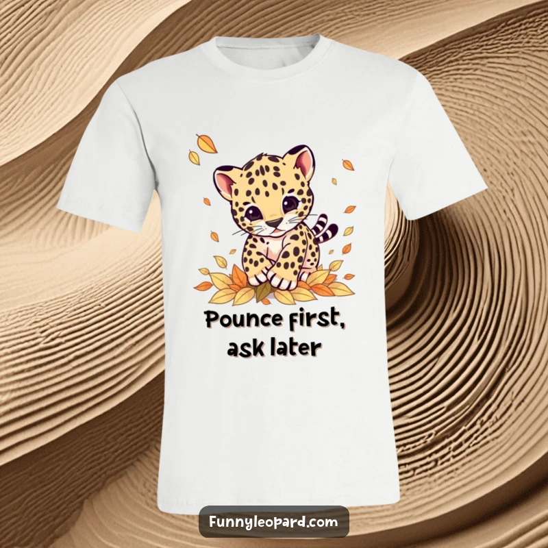 Funny t-shirt featuring a lively leopard cub mid-pounce on a pile of vibrant fall leaves, expressing pure, unadulterated fun.